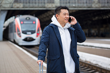 在火车站的亚洲男商务人士 玩着在电话里聊天吗企业家大厅说话商业游客车站微笑男人乘客旅行图片