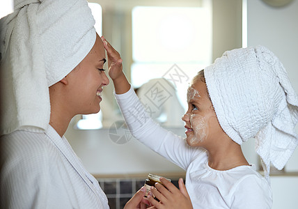 母亲和女儿在家里的水疗日里亲密无间 共度时光 小女孩在微笑和玩乐时涂抹面霜 做皮肤面部护理的快乐妈妈和孩子图片