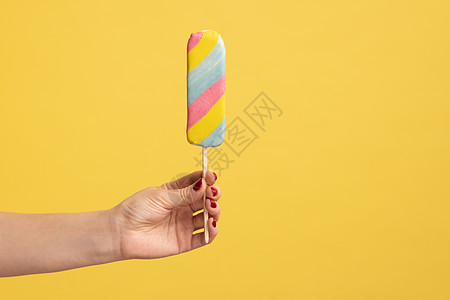 女人手拿着有色冰淇淋 在棍子 甜食广告和甜食上吃开胃饭图片
