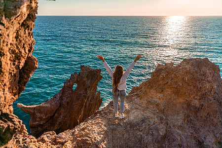 女游人 举手而立 天涯海角 见龙岩 女孩欢迎太阳 概念设计 一个成功的女人张开双臂看着夕阳悬崖地平线日落旅游支撑时段海洋地标海浪背景图片