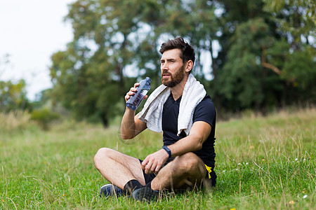 锻练训练或慢跑运动员在户外用毛巾坐在户外时精疲力尽赛跑者运动服呼吸休息森林慢跑者运动公园男性跑步图片