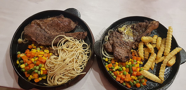 牛肉牛排和炸土豆加美味的蘑菇酱 沙拉和意大利面条 配上美丽的黑盘牛扒杂货店炙烤烹饪状物盘子食物餐厅迷迭香鱼片图片