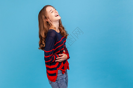歇斯底里的笑声 快乐的年轻女人穿着条纹休闲风格的毛衣 大声笑着捂着肚子 被幽默的笑话逗乐了图片