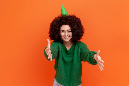 喜悦的非洲发型女子穿着绿色便衣毛衣和果冻 庆祝生日晚会 邀请客人 (笑声)图片