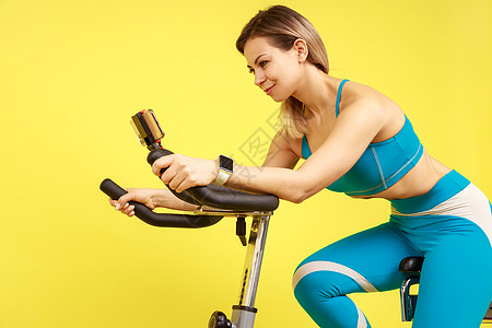 骑自行车的运动女运动员 在智能手机上看辅导录像 心血管锻炼图片