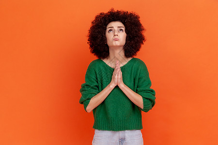 身穿绿色毛衣的有希望的非洲发型妇女举手祈祷和恳求 满怀希望地仰望着她 要求道歉图片