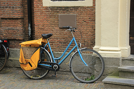 一辆旧的蓝色轻型自行车停在砖墙附近图片
