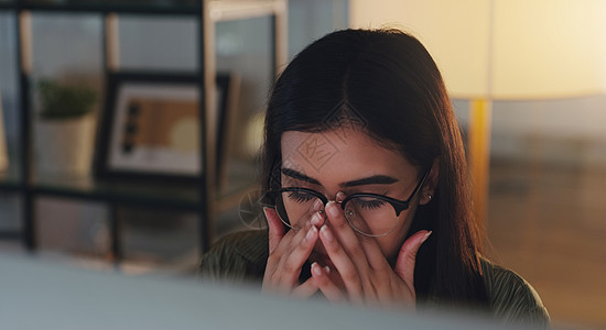 盯着这个屏幕真的很伤我的眼睛 一位年轻的女商务人士晚上在办公室用电脑工作时看起来压力很大图片