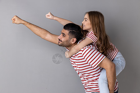 快乐的爸爸搭载女儿 使飞跃超级英雄的手 拳头向前的手势图片