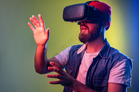 令人印象深刻的长胡子时髦男子站在VR 玩电子游戏和试图触摸的东西图片