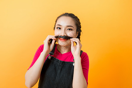 年轻女孩制作假胡子的肖像照片 在生动黄色彩色背景上被孤立 玩耍酷图片
