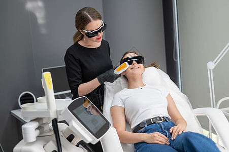 一个穿着护目镜的沙发上的女人 正在经历一个光复过程 硬体美容学皮肤科按摩治疗程序皮肤皱纹老化频率女士化妆品图片