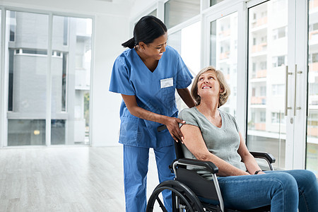 一位年轻护士照顾坐在轮椅上的年长妇女 在工作时 她需要的是心力图片