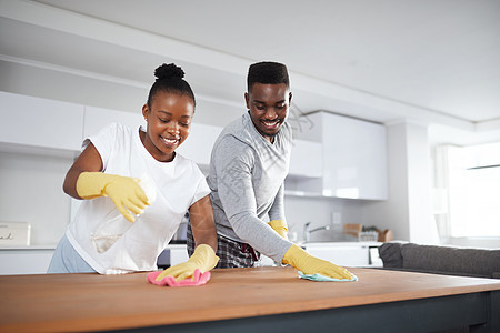 卫生的家庭是健康的家庭 一对年轻夫妇在家里打扫厨房柜台图片