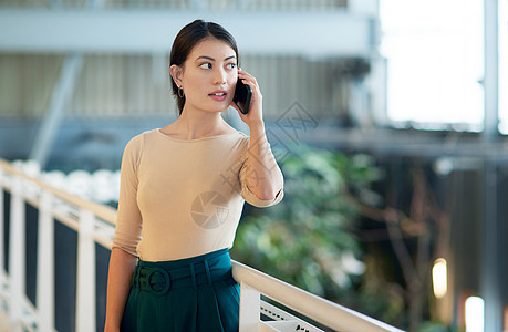 一名年轻女商务人士在办公室用手机说话 她正在打几个后续的电话图片