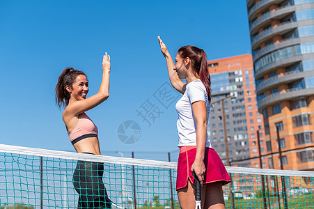 在户外法庭参加网球比赛前 两名穿运动服的高加索妇女打招呼 玩家们在比赛前击掌5次训练玩家手势快乐女孩竞赛夫妻对手爱好合伙图片