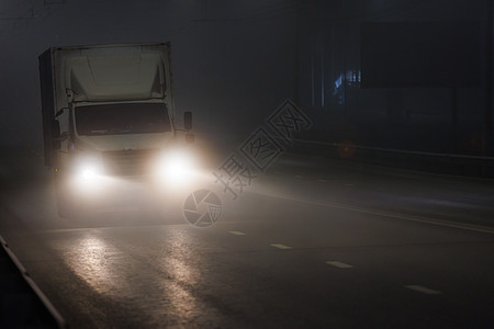 在夜雾路上行驶的小型无干的干货车车辆黑暗阴影大灯方法光束射线场景运输辉光图片