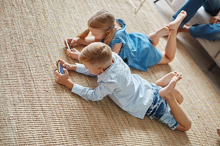 弟弟和妹妹在他们的智能手机上玩娱乐游戏 他们很聪明兄弟电话手表教育闲暇视频童年训练女孩姐姐背景图片