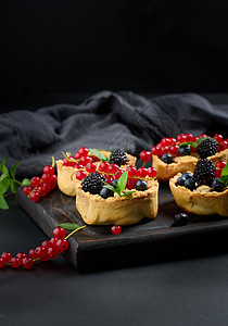 在黑桌上洒满粉末糖的果冻和红花盆黑色棕色桌子传统甜点糕点食物水果脆皮白色图片
