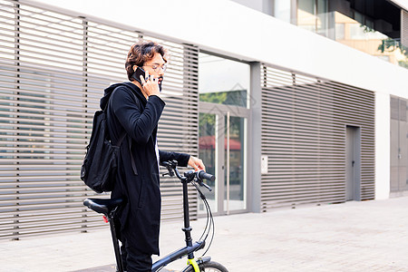年轻人用折叠自行车 在手机上说话图片