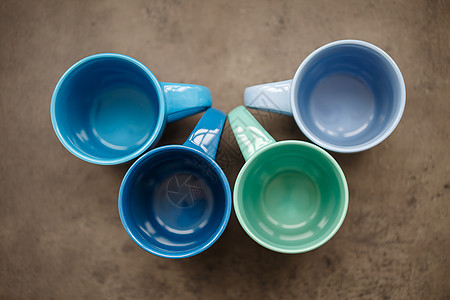 灰色背景上四杯不同颜色的茶杯橙子红色绿色团体陶瓷厨具盘子陶器咖啡蓝色图片