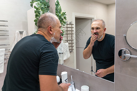 早上洗手间用泡沫擦刮剃刀的人刮胡子护理中年头发奶油胡子皮肤凝胶胡须成人图片