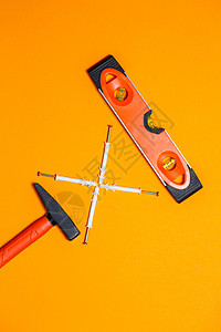 维修工具 钉子锤 水平仪 橙色背景墙上的销钉 向导工具包填料修理案件工艺测量建筑锤子手套钻头技术图片