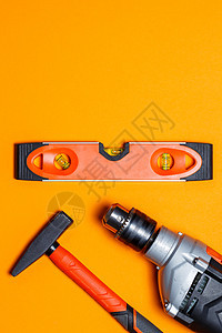 修理家用的工具 橙色背景上的钉子锤 水平仪和钻孔器 向导工具包作坊钻头维修金属装修项目技术修理工木制品木头图片
