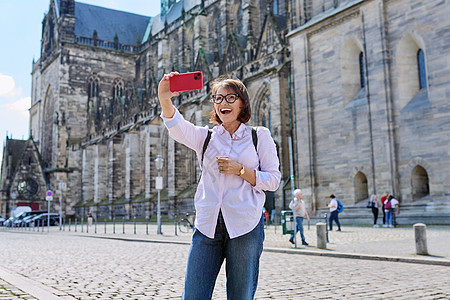 在古代欧洲大教堂前自拍的女旅游者 妇女电话历史冒充假期手机旅游历史性宗教寺庙城市图片