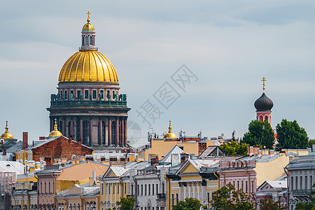 多云天气下 圣以撒大教堂巨大的金色圆顶穿过圣彼得堡涅瓦河堤岸的房屋屋顶观光城市文化下雨教会柱廊旅游历史地标中心图片