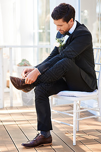 一个英俊的年轻新郎坐在椅子上 将鞋带绑在结婚日上的照片拍得一整片 我当时正准备和他共进晚餐图片