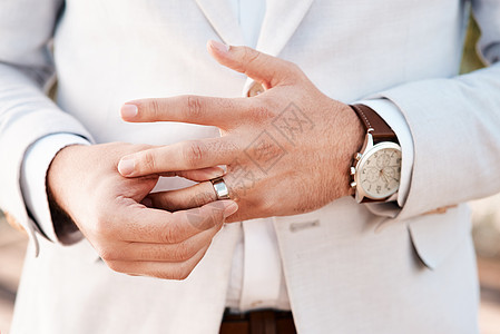这枚结婚戒指是一生承诺的象征 一个面目全非的新郎在婚礼当天调整他的戒指背景图片