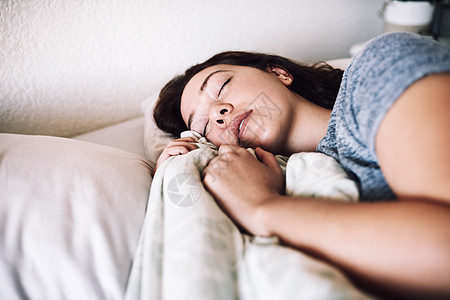 充足的睡眠是一种自我保健的方式 一个迷人的年轻女人早上在家里睡在她的床上图片