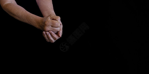 一位年长女性在黑色背景特写上皱纹的手图片