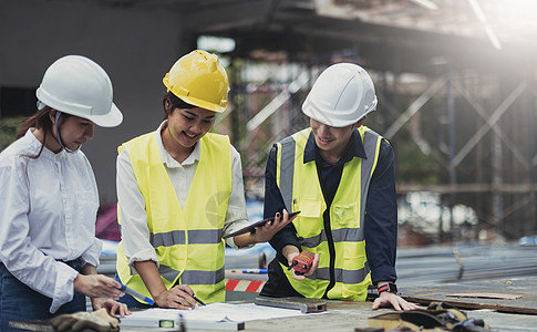 三位专家与土木工程师一起检查商业建筑施工现场 工业建筑房地产项目 投资者在背景住宅 混凝土模板框架中使用笔记本电脑头盔成年人男人图片