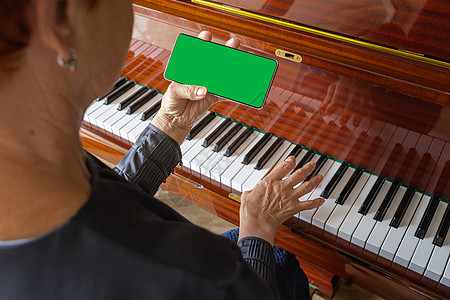 老女人弹钢琴 看电话笔记 智能手机的夏洛玛密钥图片
