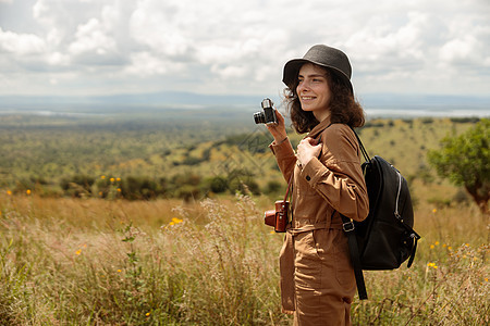快乐的女游客 带着摄影相机穿过热带草原图片