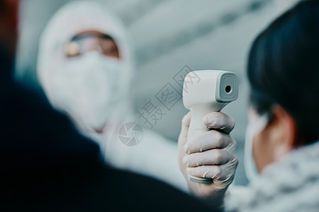 医护人员 穿着防护服扫描 covid 患者的温度以确保安全以防止病毒大流行 穿着防护服的医生用温度计检查潜在的爆发图片