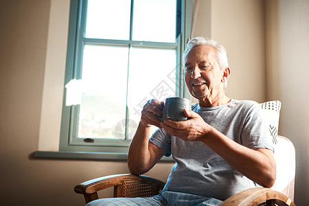 嗯 没有什么比早上喝杯咖啡更好的了 一个快乐的老人拿着一杯咖啡坐在家里的扶手椅上图片