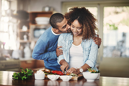 浪漫 充满爱心和关怀的男朋友在厨房做饭时拥抱他的女朋友并表达爱意 一对夫妇在家里做饭或沙拉时亲吻和拥抱图片