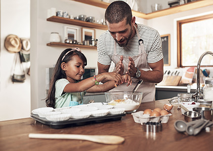 幸福是拥有一个庞大 充满爱心 关怀备至 关系密切的家庭 一位父亲在家里的厨房里教他的女儿如何烘焙图片