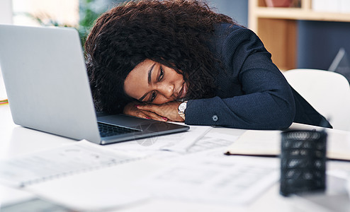 一位年轻女商务人士睡在现代办公室的办公桌前 她正在工作图片