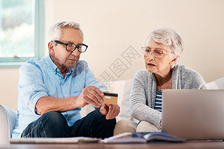 并非每笔交易都需要去银行 一对老年夫妇在家里处理文书工作时使用信用卡图片