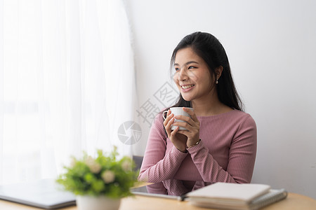 学习在线学习时 用一杯咖啡来喝咖啡的亚洲女性平凡而快乐图片