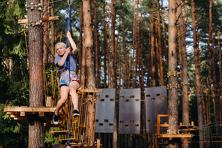 女孩在绳子镇路过障碍物 一个女孩在林绳子公园挑战操场森林乐趣冒险安全城市树林危险自由图片