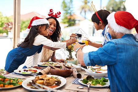 圣诞节本来就是要和家人一起度过的 一个美丽的年轻家庭在户外一起享用圣诞午餐时分享干杯图片