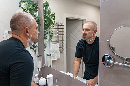 早上洗手间用泡沫擦刮剃刀的人镜子奶油凝胶浴室刮胡子胡子成人男性皮肤隔断图片