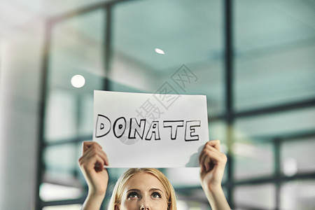 一名妇女在公司办公室举着需要支持的牌子 请求捐赠 慈善和帮助 志愿者向社区和企业寻求帮助和众筹图片