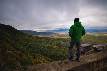 一个男人徒步旅行 站在山顶的闪亮夹克图片