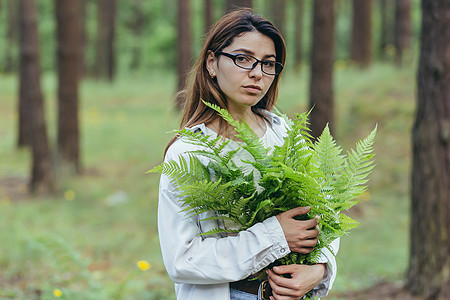 在树林里的女人拥抱着一束野生的花束 一个年轻的积极分子保护森林季节护理皮肤植物群成人蕨类化妆品公园头发女孩图片